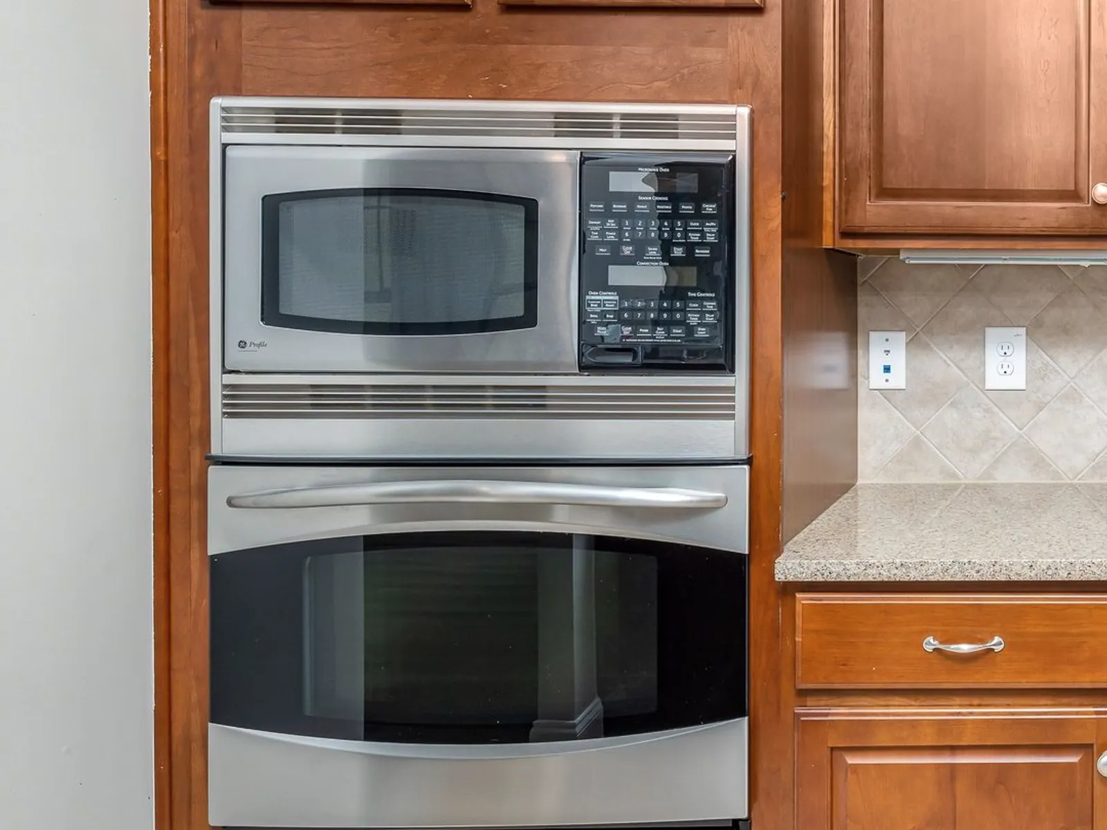 Built-in microwave above a wall oven in wood kitchen cabinets