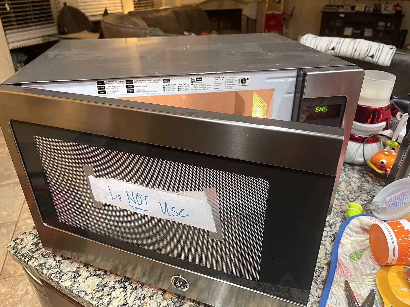 Countertop microwave with the door open and a handwritten Do not use note taped to the glass